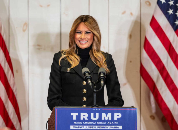 shutterstock_1844845672.jpg featured image Woman speaking at Trump podium, two American flags present.
