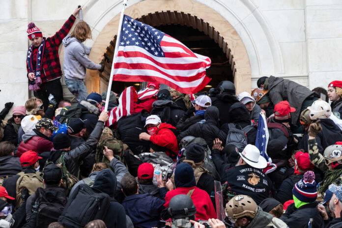 shutterstock_1889190787.jpg featured image Crowd with American flags storming a building entrance.