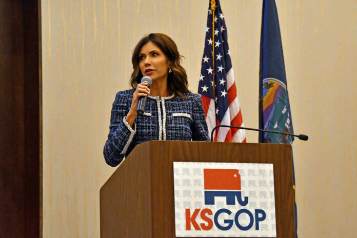 shutterstock_1962398782.jpg featured image Kristi Noem speaking at KS GOP event podium.