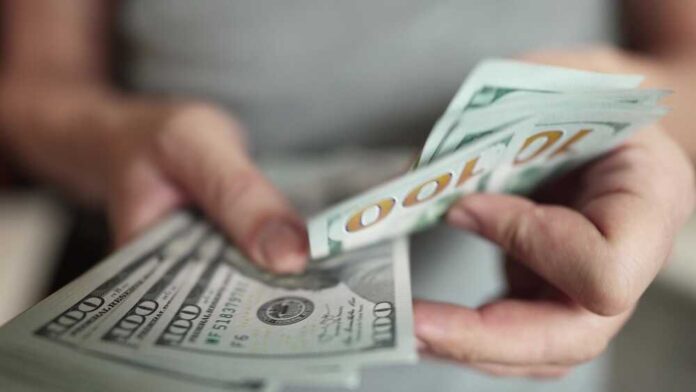 shutterstock_2159975017.jpg featured image Hands holding stack of one hundred dollar bills