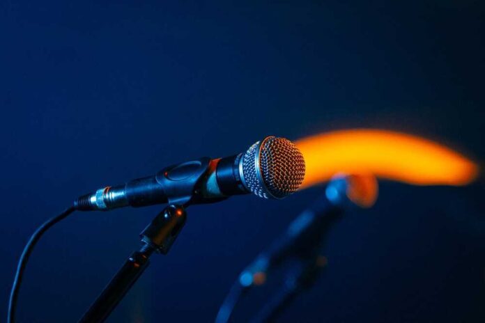shutterstock_24205293711.jpg featured image Close-up of a microphone on a stand, dark background.