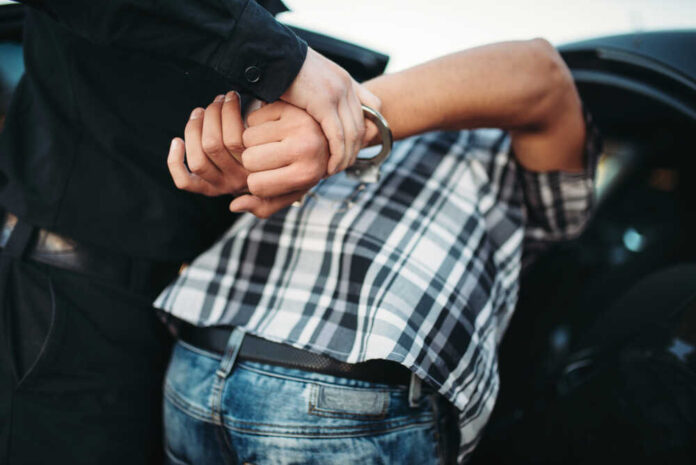 shutterstock_1144500824.jpg featured image Person in handcuffs arrested by police officer.