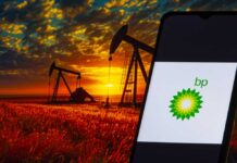BP logo on phone with oil pumps backdrop