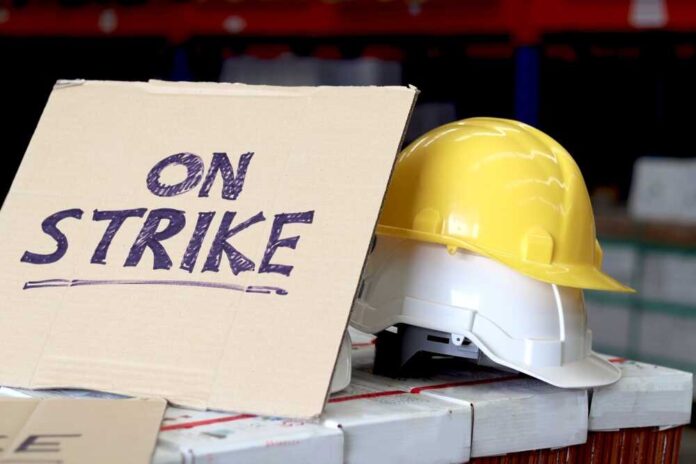 shutterstock_2417329727.jpg featured image Sign reads On Strike near yellow hardhat