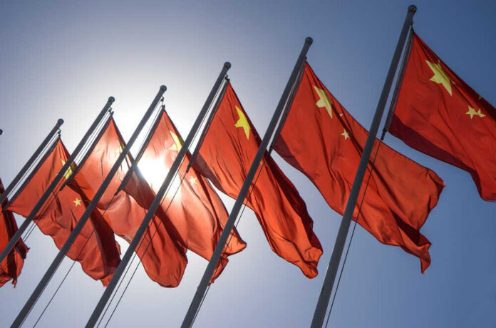 shutterstock_325058183.jpg featured image Chinese flags waving under a clear sky.