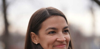 Alexandria Ocasio-Cortez, or AOC, smiling woman with long hair.