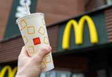 Hand holding McDonalds cup in front of sign