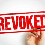 Hand holding a marker writing revoked stamp