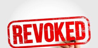 Hand holding a marker writing revoked stamp