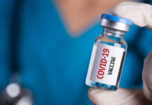 Person holding a vial labeled COVID-19 Vaccine.