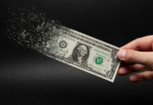 Dollar bill disintegrating while held by hand.