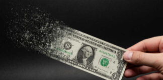 Dollar bill disintegrating while held by hand.