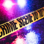 Crime scene tape with flashing lights in background