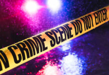 Crime scene tape with flashing lights in background