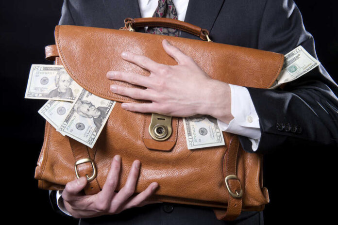 Person clutching leather bag with money sticking out.