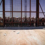 People standing behind the border wall