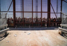 People standing behind the border wall