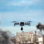 Drone flying over urban area with smoke plumes