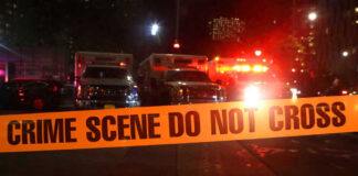 Crime scene tape with emergency vehicles in background