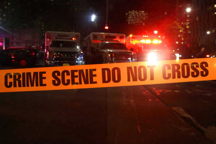 Crime scene tape with emergency vehicles in background