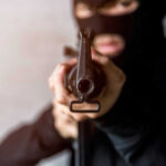 Chilling Twist: Couple Killed With Own Gun Person in balaclava aiming rifle at the camera
