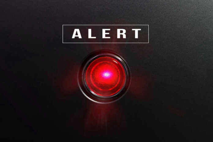 Red alert light against black background text ALERT
