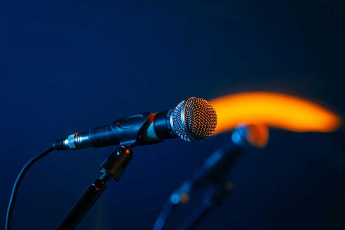 Close-up of a microphone on a stand, dark background.