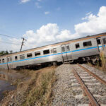 Deadly Train Crash — 13 Killed Derailed train car leaning off the tracks near a body of water