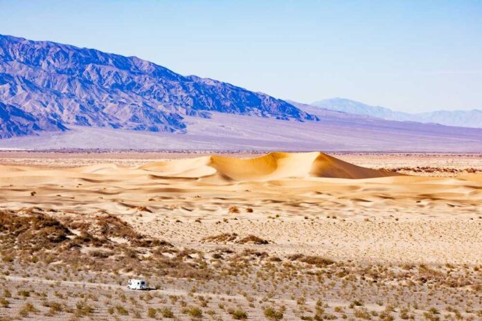 Vast desert landscape with sand dunes and mountains in the background