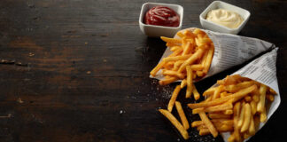 Two servings of french fries in paper cones with ketchup and mayonnaise