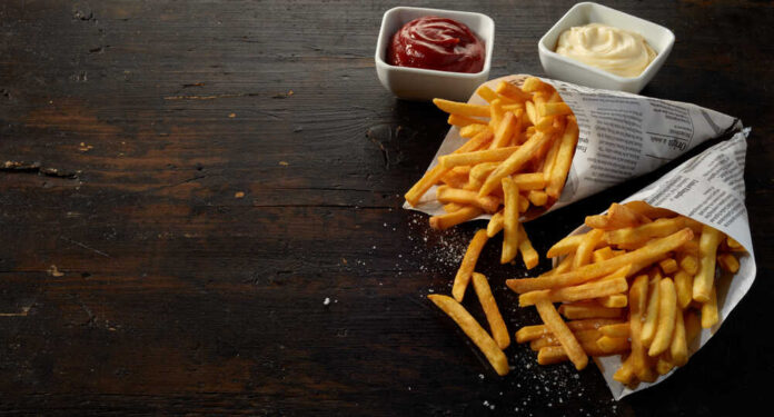 Two servings of french fries in paper cones with ketchup and mayonnaise