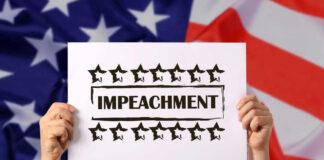 Hands holding impeachment sign over American flag.