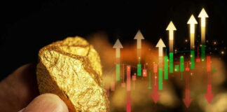 Hand holding gold nugget with financial market chart.