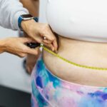 A person measuring anothers waist with a tape measure