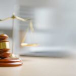 A wooden gavel and scales of justice on a desk