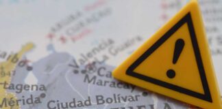 A close-up of a map of Venezuela with a yellow warning sign