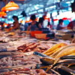 A bustling seafood market with various types of fish and seafood displayed