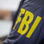 Person wearing FBI jacket, letters in yellow.