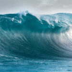 A large ocean wave curling with vibrant blue hues