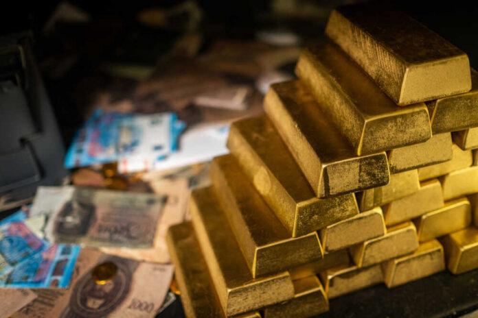 Stack of gold bars next to scattered banknotes and coins
