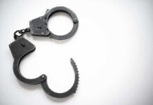 Open metal handcuffs on white background.