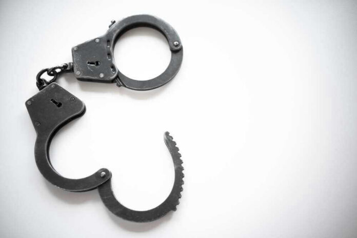 Open metal handcuffs on white background.