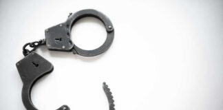 Open metal handcuffs on white background.