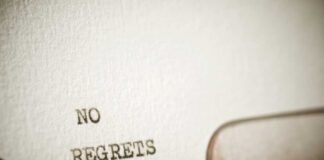 Close-up of a typewriter with the words 'NO REGRETS' typed on paper
