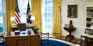 Presidential office with desk, flags, and portraits.