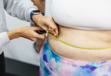 A person measuring anothers waist with a tape measure
