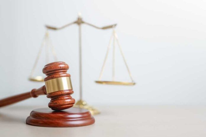 shutterstock_2647382551.jpg A wooden gavel in front of a balance scale symbolizing justice