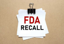 A notice labeled 'FDA RECALL' clipped to white papers on a brown background