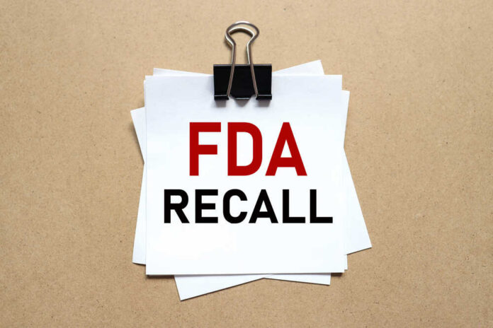 shutterstock_1995441497.jpg A notice labeled 'FDA RECALL' clipped to white papers on a brown background