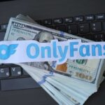 OnlyFans logo placed on a stack of hundred dollar bills